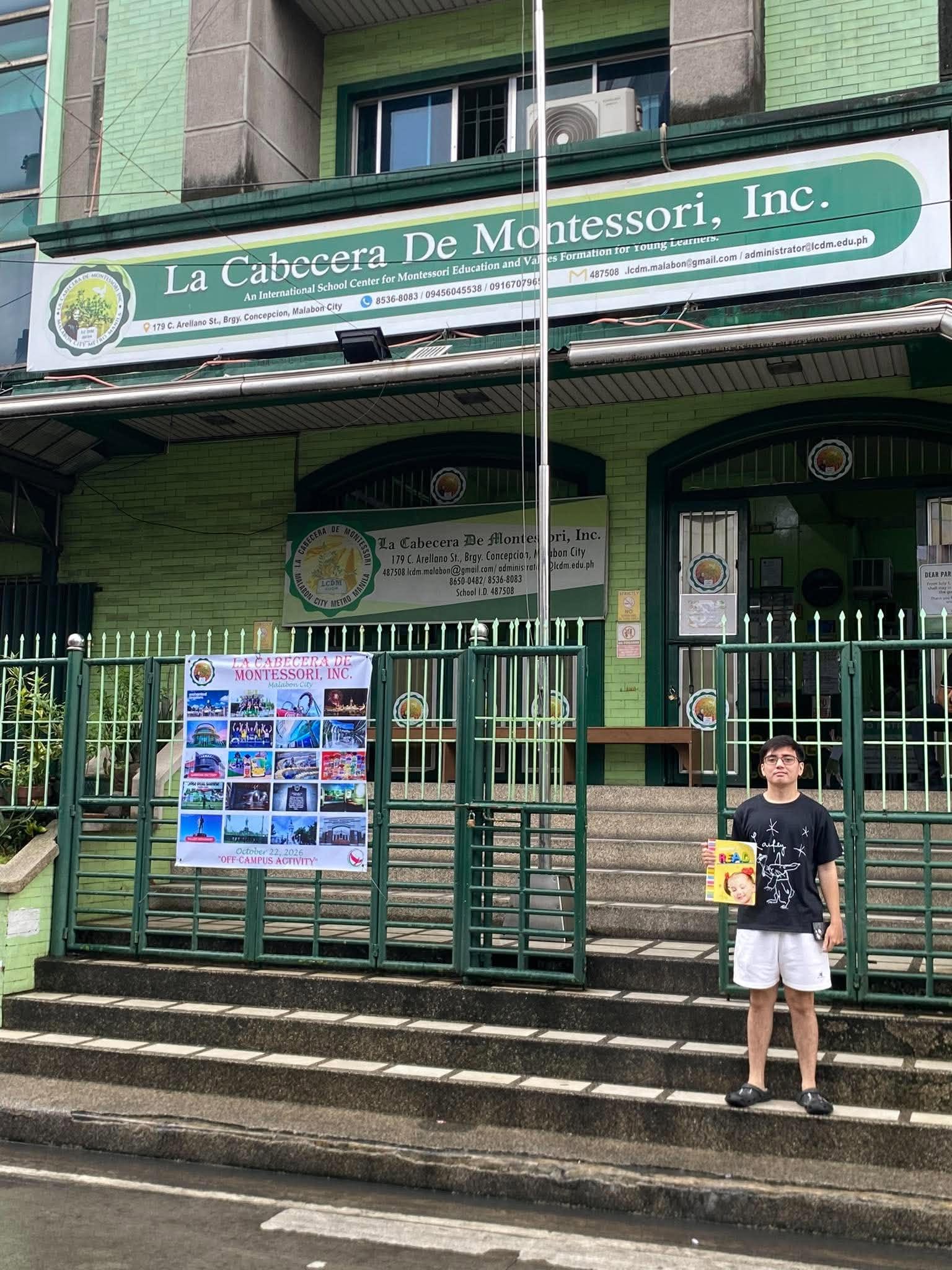 Someone holding a READ picture book in front of the school entrance